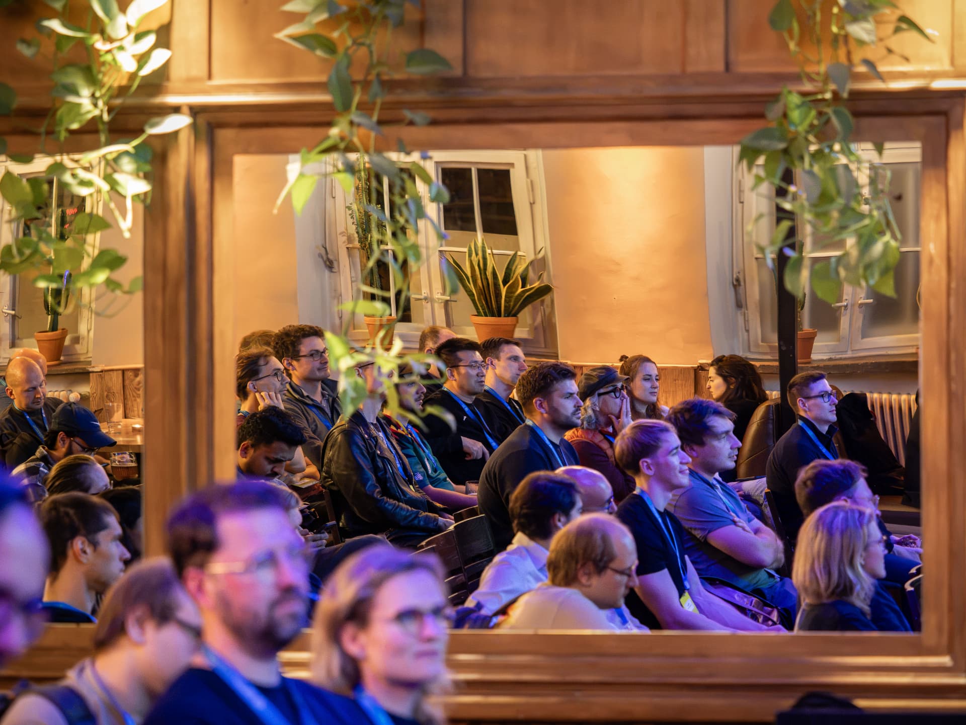 Audience watching a session seen through the wooden window frame at Alte Turnhalle