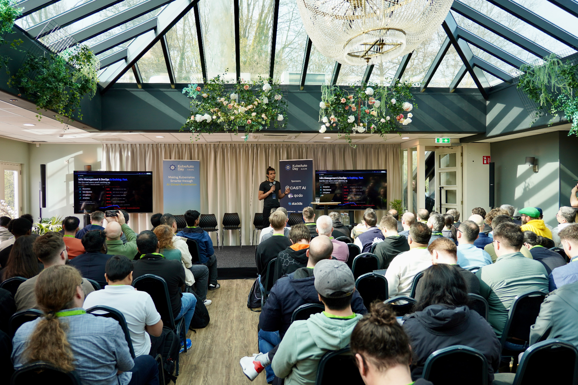 Speaker on stage under the glass roof at KubeAuto Day
